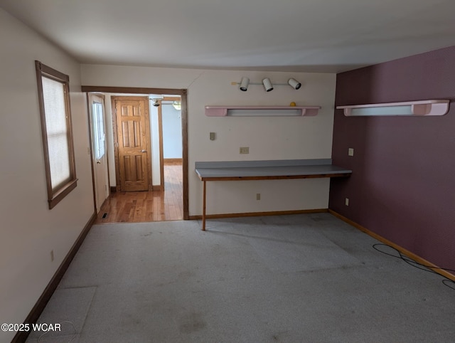 interior space featuring light carpet and baseboards