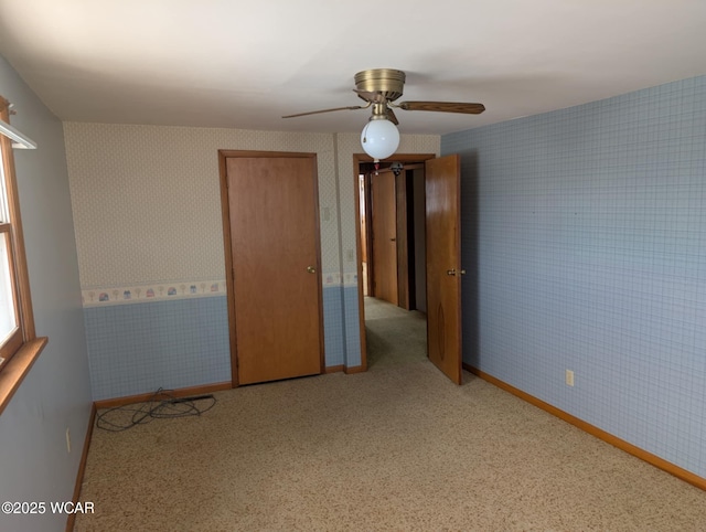 interior space with light carpet, ceiling fan, baseboards, and wallpapered walls