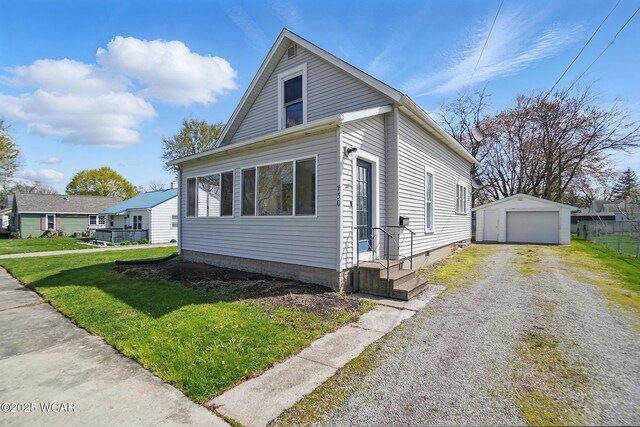 view of front of home featuring a front lawn, driveway, an outbuilding, and a garage