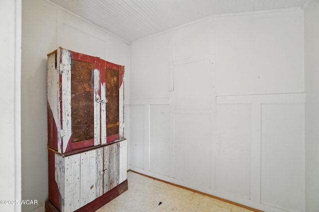 empty room featuring a decorative wall, tile patterned floors, and ornamental molding