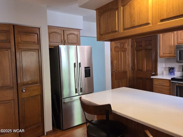 2134 Wyandot Dr, Lima, OH 45806 - kitchen with appliances with stainless steel finishes, light countertops, brown cabinetry, dark wood finished floors, and a breakfast bar area