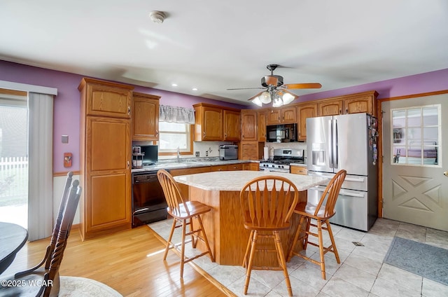 1543 Wonderlick Rd, Lima, OH 45805 - kitchen featuring a breakfast bar area, a kitchen island, brown cabinetry, and black appliances
