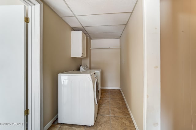 washroom with cabinet space, light tile patterned floors, washing machine and dryer, and baseboards