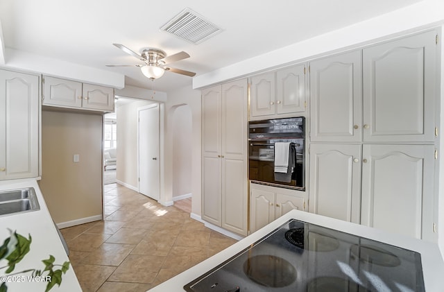 kitchen featuring sink, oven, ceiling fan, white cabinets, and light tile patterned flooring