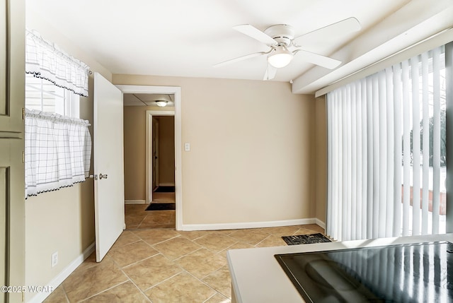 empty room featuring light tile patterned floors, a ceiling fan, and baseboards