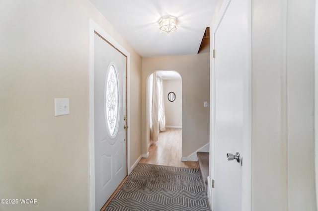 foyer entrance with arched walkways and baseboards