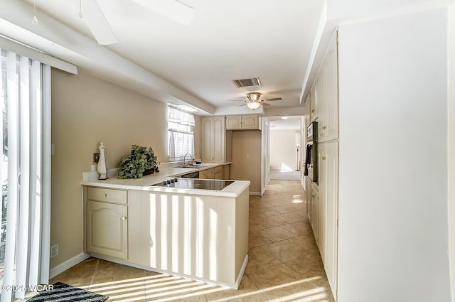 kitchen with black electric stovetop, kitchen peninsula, ceiling fan, and light tile patterned floors