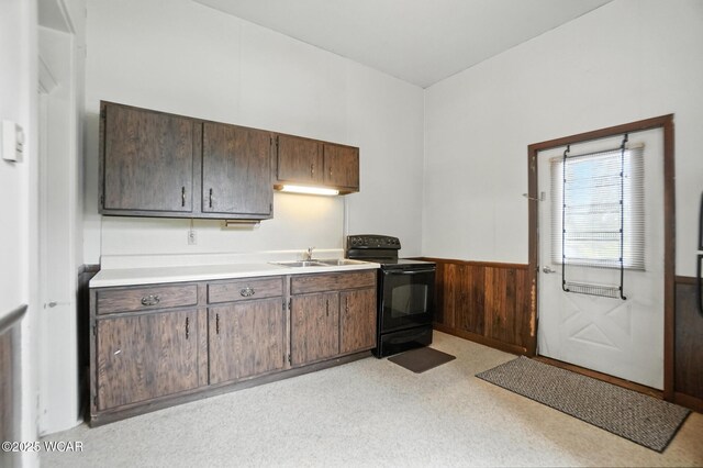 307 N Jefferson St, Van Wert, OH 45891 - kitchen featuring black range with electric cooktop, a wainscoted wall, light countertops, wooden walls, and dark brown cabinetry