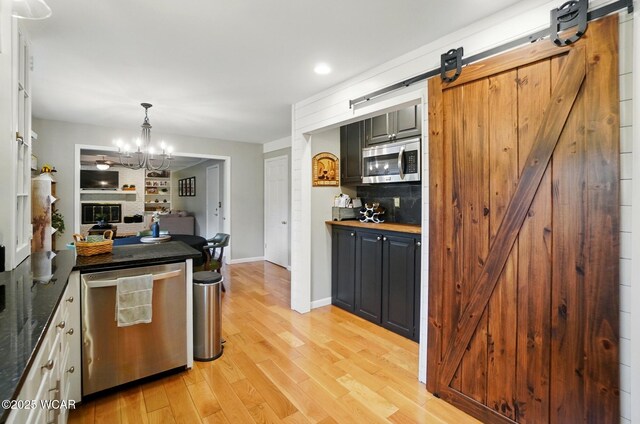 2357 London Dr, Lima, OH 45805 - kitchen featuring a barn door, stainless steel appliances, a chandelier, light wood finished floors, and dark countertops
