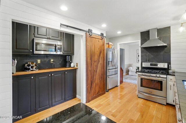 2357 London Dr, Lima, OH 45805 - kitchen featuring stainless steel appliances, wall chimney range hood, light wood-style floors, tasteful backsplash, and recessed lighting