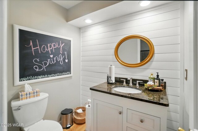 2357 London Dr, Lima, OH 45805 - half bathroom with vanity, toilet, wooden walls, and wood finished floors