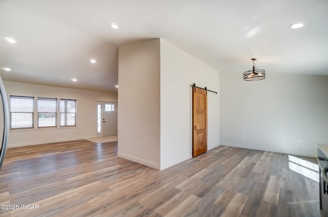 spare room with light wood-style floors, a barn door, vaulted ceiling, and recessed lighting