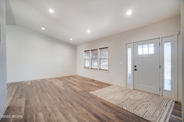 foyer entrance featuring baseboards, lofted ceiling, recessed lighting, and light wood finished floors