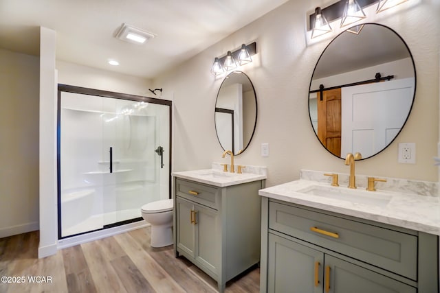 bathroom featuring a sink, a shower stall, two vanities, and wood finished floors