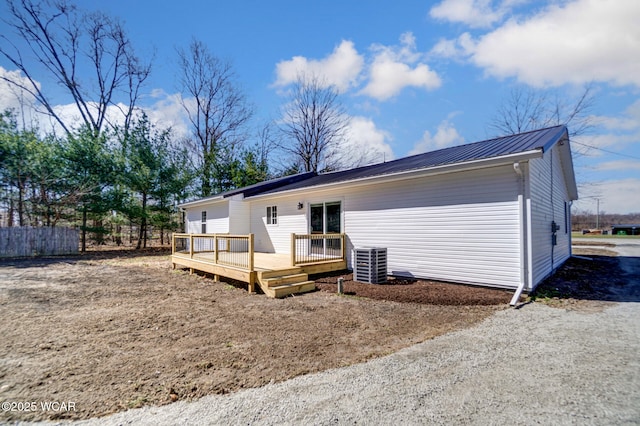 back of property featuring fence, a deck, and metal roof