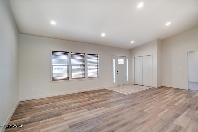 foyer entrance featuring baseboards, lofted ceiling, light wood finished floors, and recessed lighting