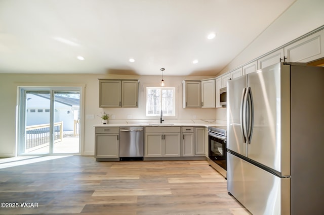 kitchen featuring light wood finished floors, recessed lighting, appliances with stainless steel finishes, a sink, and gray cabinetry