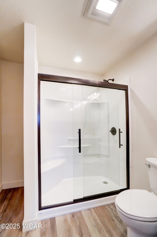 bathroom featuring toilet, a shower stall, wood finished floors, baseboards, and visible vents
