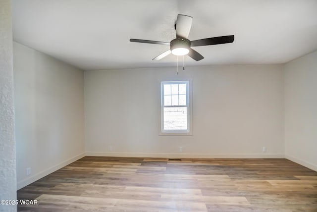 unfurnished room featuring baseboards, wood finished floors, and a ceiling fan