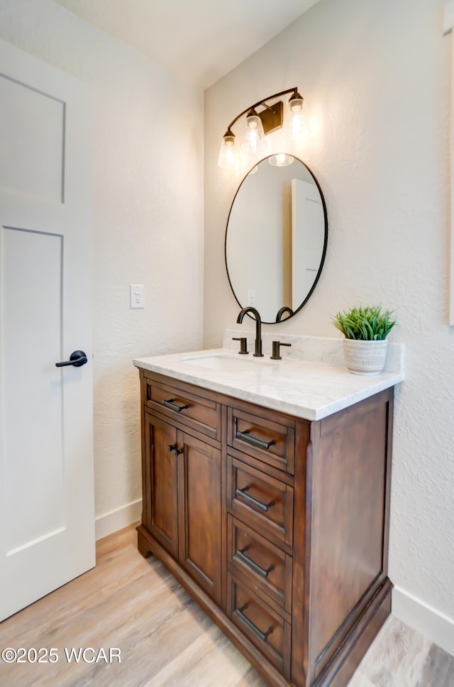 bathroom featuring vanity, baseboards, and wood finished floors