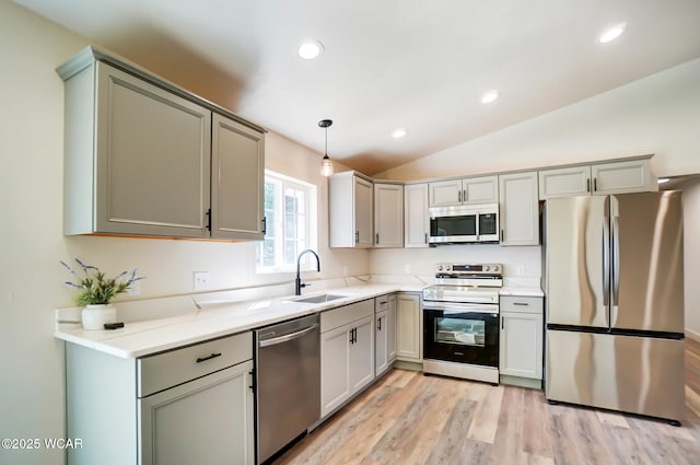 kitchen featuring vaulted ceiling, gray cabinets, a sink, and stainless steel appliances