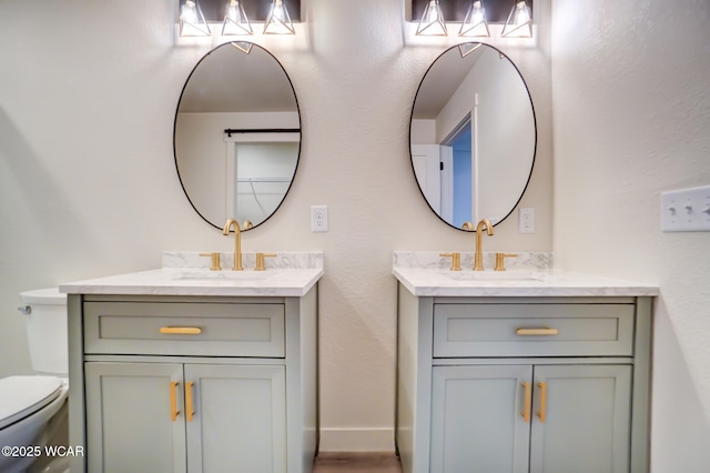 full bathroom featuring toilet, a sink, and two vanities