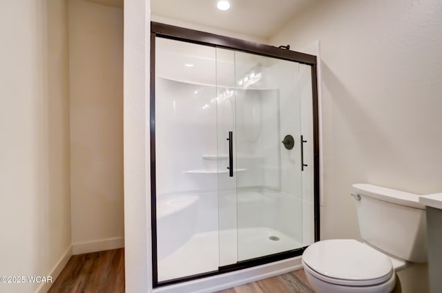 full bathroom featuring toilet, a stall shower, baseboards, and wood finished floors
