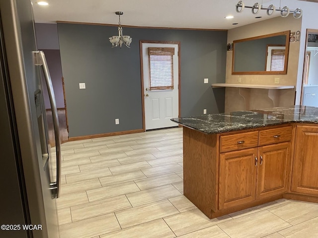 1421 Krendl Dr, Van Wert, OH 45891 - kitchen with stainless steel fridge, brown cabinetry, a chandelier, dark stone countertops, and pendant lighting