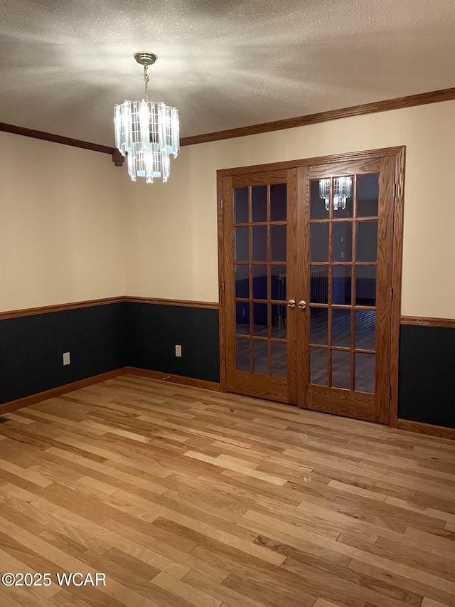 1421 Krendl Dr, Van Wert, OH 45891 - unfurnished dining area featuring a chandelier, wood finished floors, ornamental molding, wainscoting, and french doors