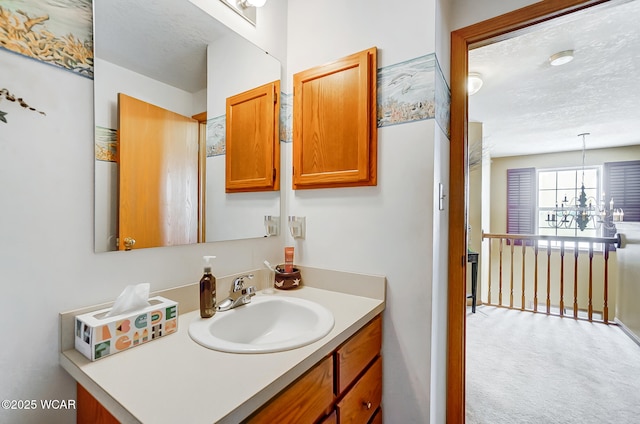 bathroom with a textured ceiling, an inviting chandelier, and vanity