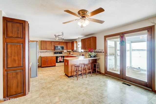 kitchen with light countertops, a sink, a peninsula, stainless steel appliances, and visible vents