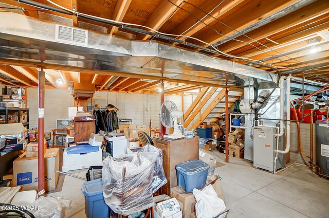 unfinished basement featuring heating unit, visible vents, and water heater