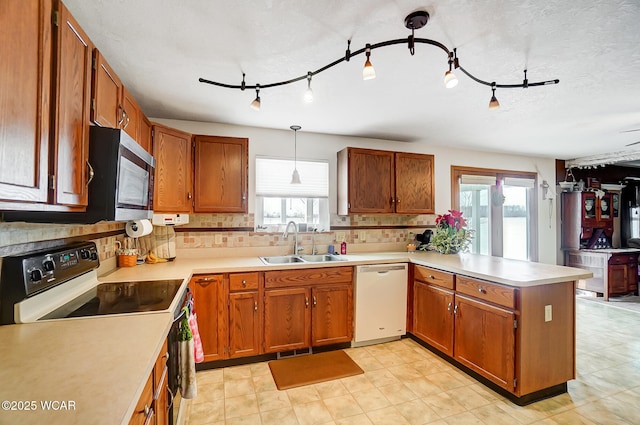 kitchen with a sink, dishwasher, a peninsula, stainless steel microwave, and electric range