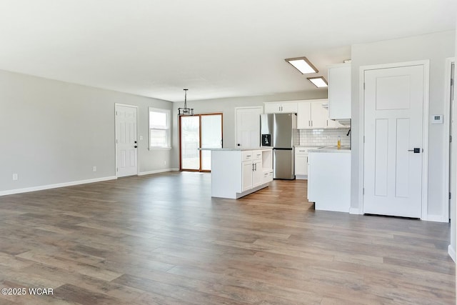 kitchen with white cabinetry, stainless steel fridge, light wood-type flooring, and open floor plan
