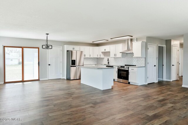 kitchen with a center island, appliances with stainless steel finishes, a sink, wall chimney range hood, and backsplash