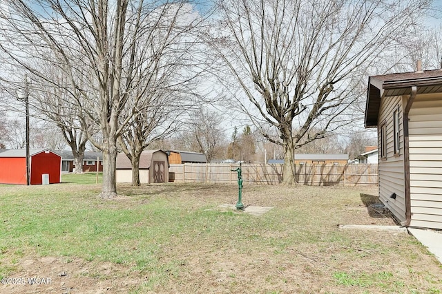 view of yard with an outdoor structure, fence, and a storage shed
