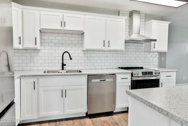 kitchen featuring white cabinets, stainless steel appliances, a sink, light wood-type flooring, and wall chimney range hood