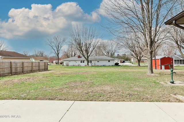 view of yard featuring a storage unit, fence, and an outdoor structure