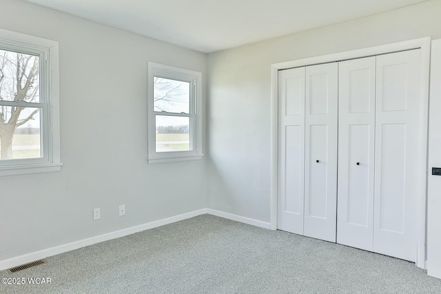 unfurnished bedroom featuring baseboards, visible vents, a closet, and carpet floors