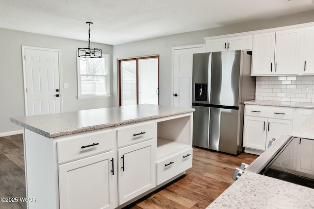 kitchen with white cabinetry, stainless steel fridge, tasteful backsplash, pendant lighting, and wood finished floors