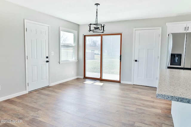 interior space featuring light wood finished floors, baseboards, and a notable chandelier