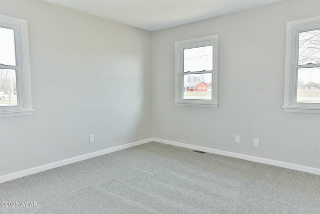 carpeted empty room featuring baseboards and visible vents