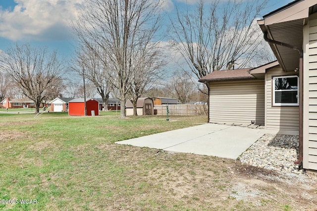 view of yard featuring a storage unit, fence, an outdoor structure, and a patio