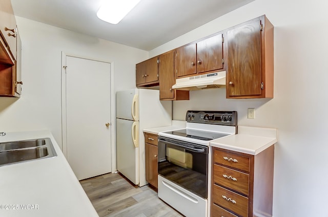 kitchen with electric range oven, light hardwood / wood-style floors, sink, and white refrigerator