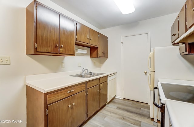 kitchen featuring white appliances, sink, and light wood-type flooring