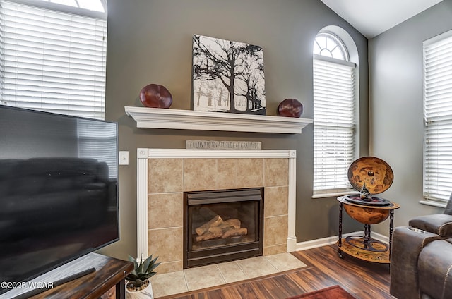 interior space featuring a tiled fireplace, hardwood / wood-style floors, and lofted ceiling