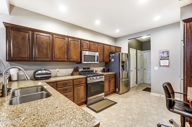 kitchen with light tile patterned flooring, appliances with stainless steel finishes, sink, and light stone counters