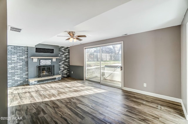 unfurnished living room featuring baseboards, a brick fireplace, wood finished floors, and a ceiling fan