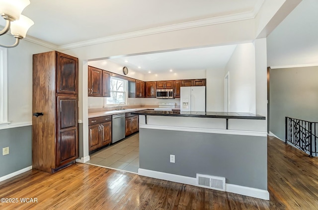 kitchen featuring light wood-type flooring, stainless steel appliances, visible vents, and crown molding