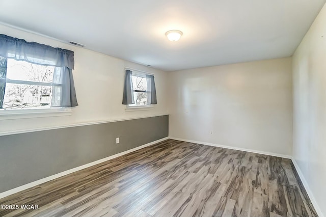 unfurnished room featuring visible vents, baseboards, and wood finished floors